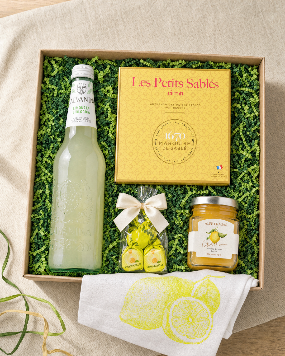 Gourmet Geschenk Kleine Zitronenfreude – Geschenkbox von oben mit Zitronen Bio-Limonade, Cuneesi Limoncello, Zitronen Marmelade, Zitronen Keksen und Geschirrtuch Zitrone
