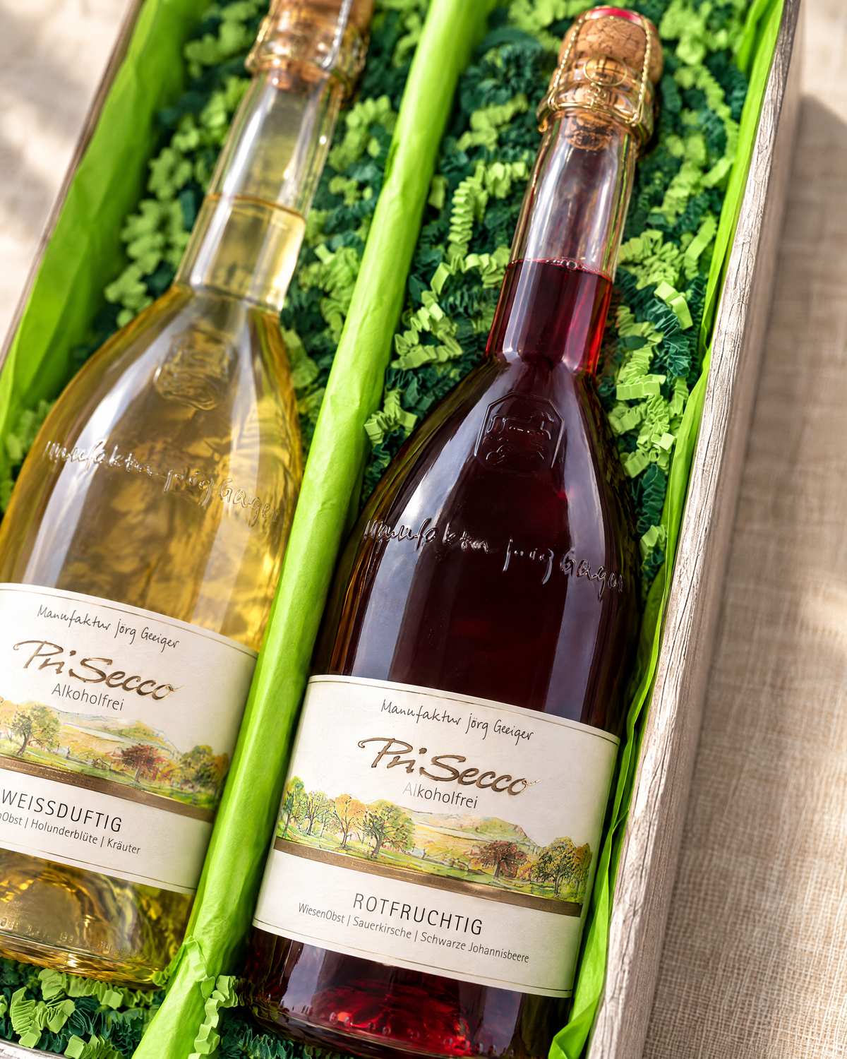 PriSecco Rotfruchtig 750 ml im Geschenkset, Detailaufnahme im Zweierkarton mit hellgrünem Papier und gemischter grüner Papierwolle