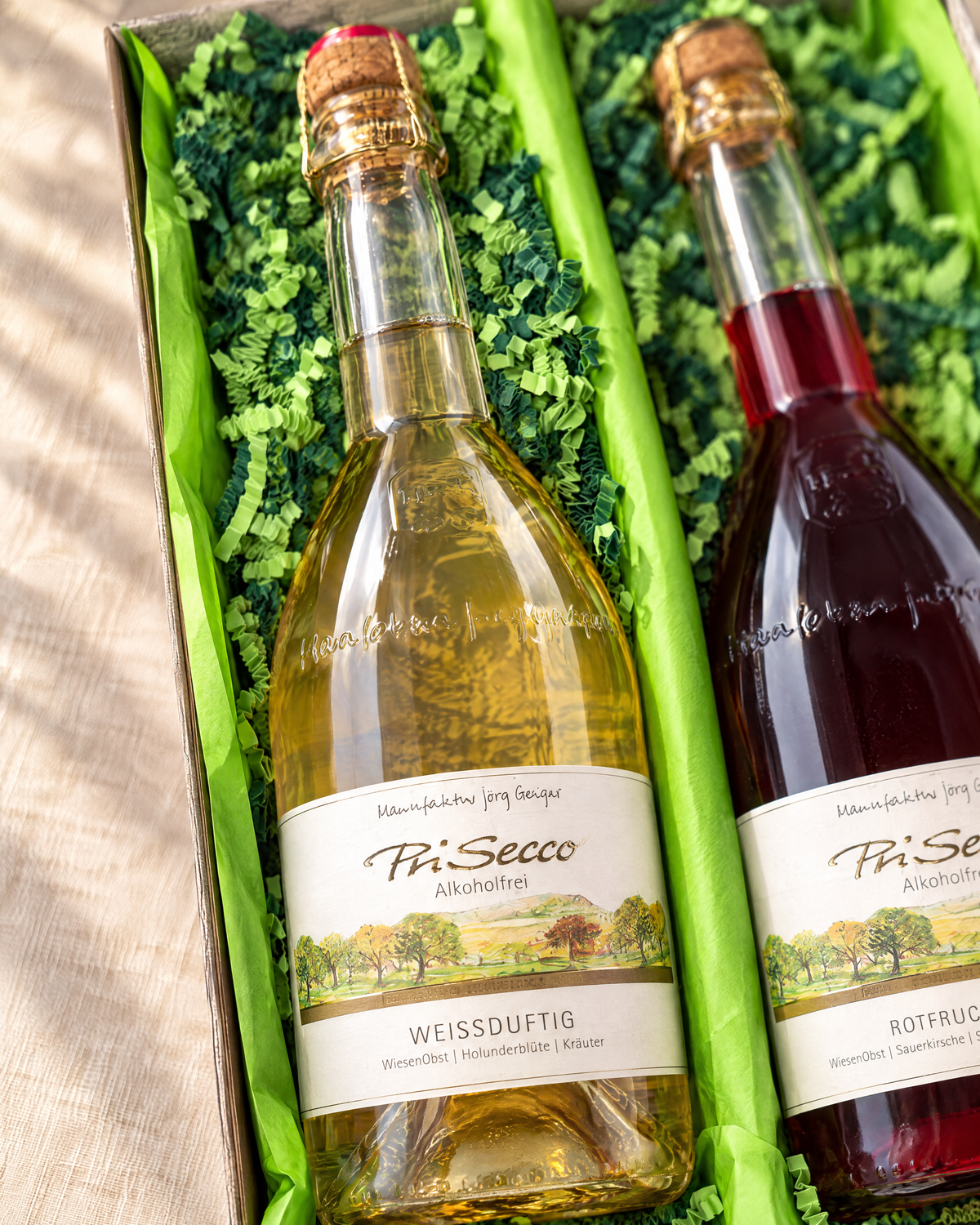 PriSecco Weißduftig 750 ml im Geschenkset, Detailaufnahme im Zweierkarton mit hellgrünem Papier und gemischter grüner Papierwolle
